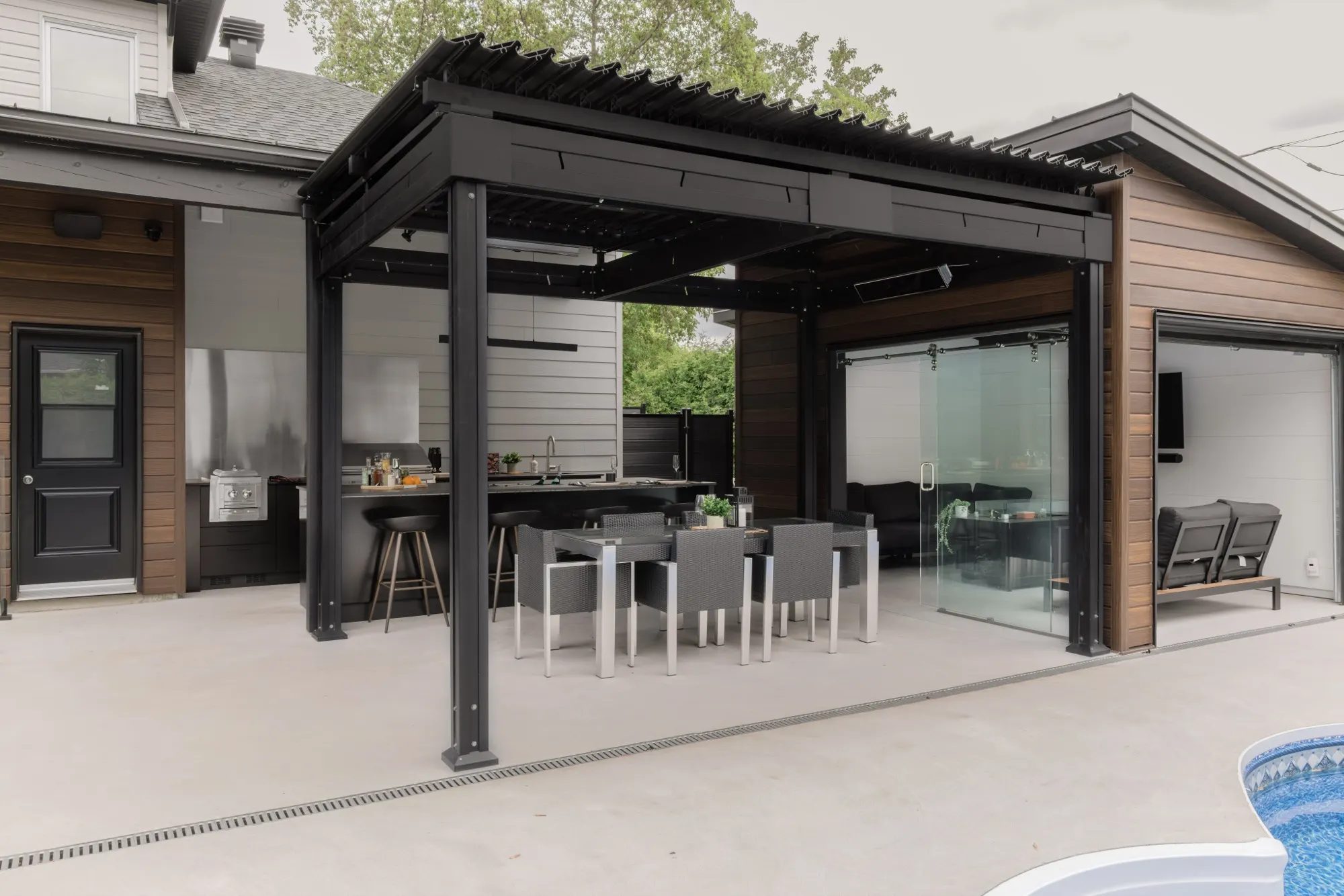 Cuisine extérieure familiale sous pergola avec vue sur la piscine