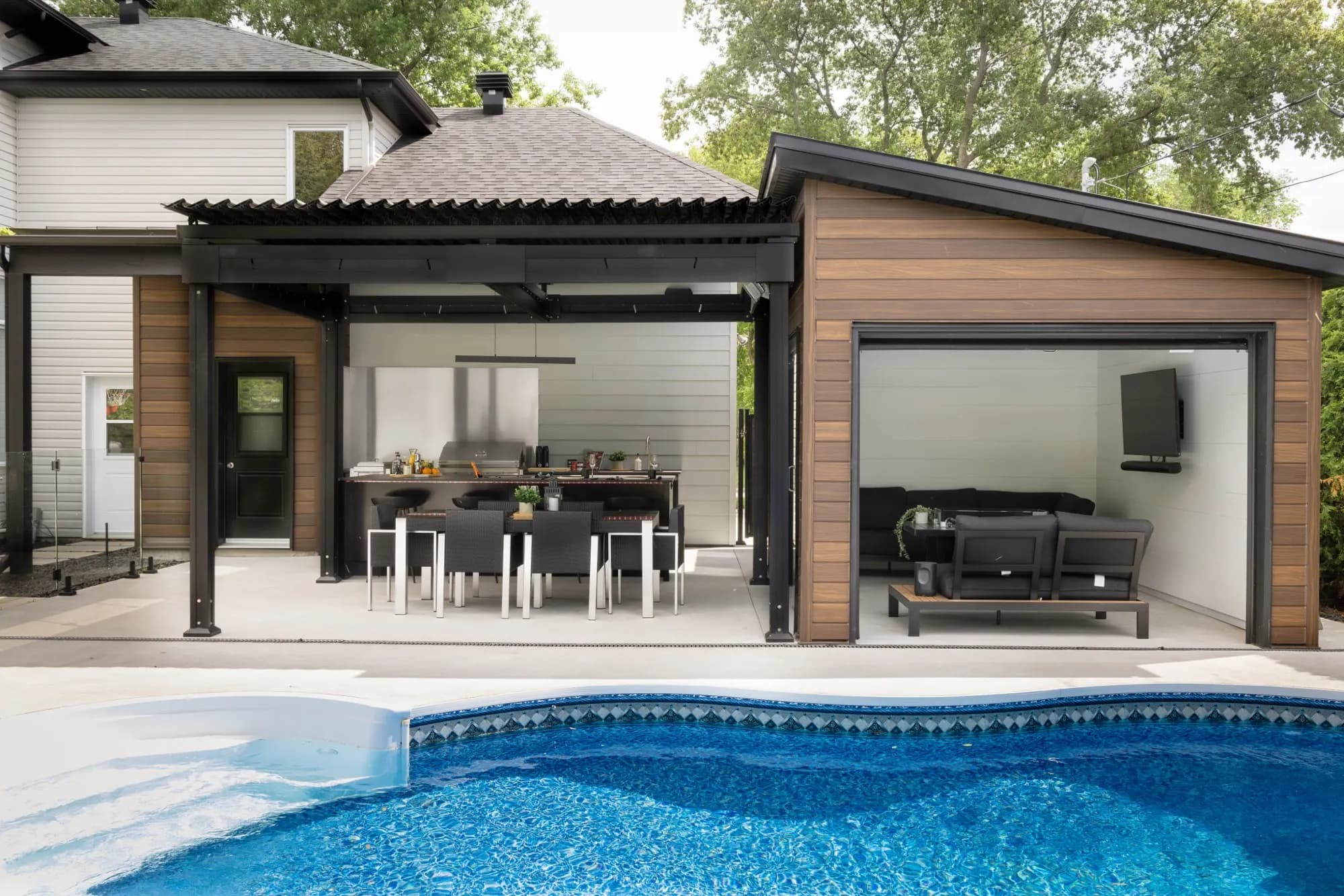 Cuisine extérieure sous pergola noire avec îlot, au bord d'une piscine à L'Assomption