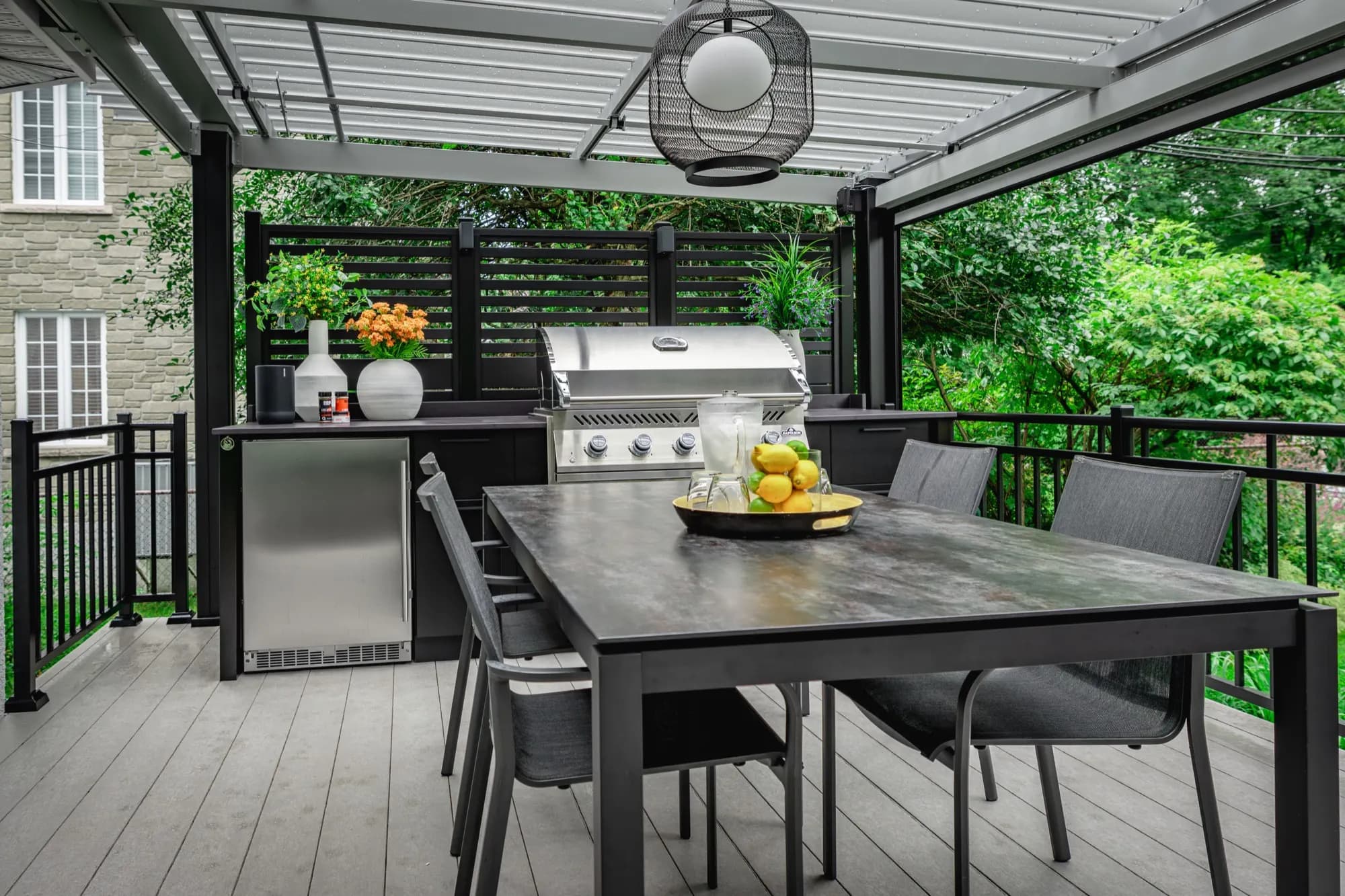 Cuisine extérieure noire avec gril encastré sur une terrasse couverte à Blainville